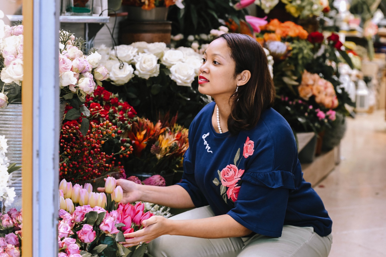 Christy thoughtfully choosing flowers at a flower market.