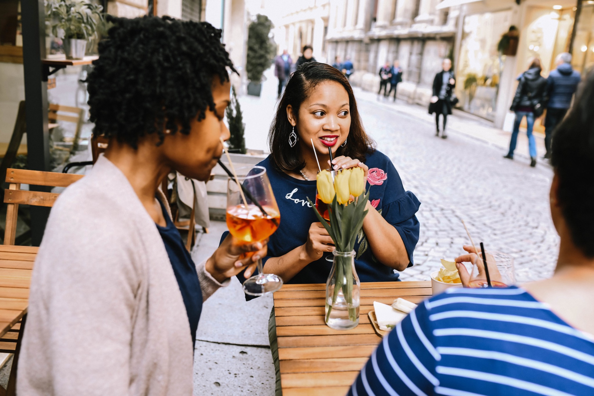 Christy sharing drinks and conversation with friends at an outdoor table.