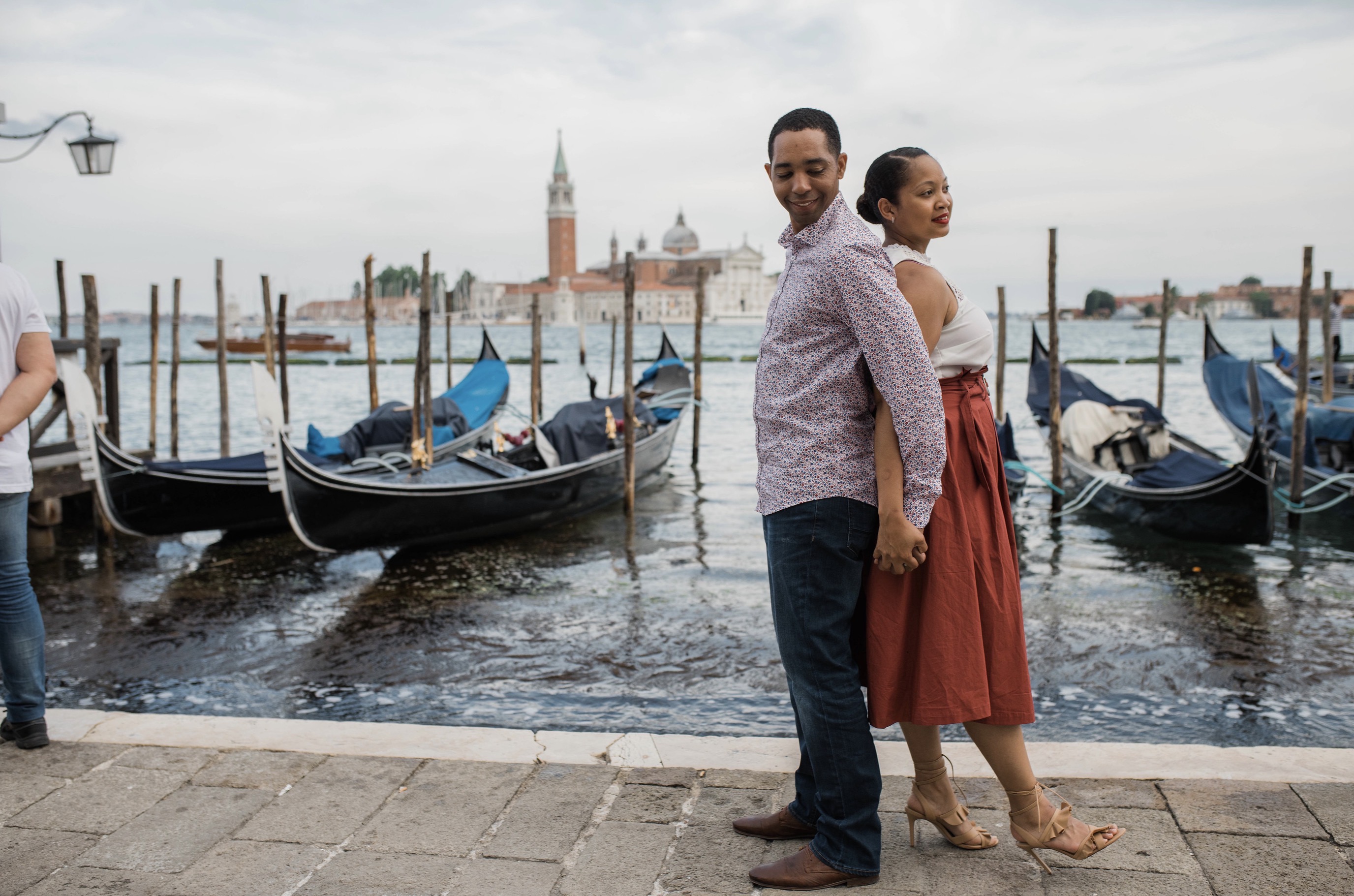 Christy and her husband standing together beside the gondolas in Venice.